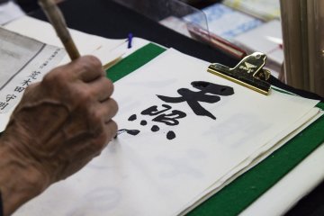 Okada shows how calligraphy is done at a calligraphy shop