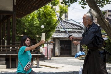 Okada slicing up a daikon held by a volunteer