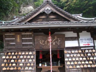 A small, simple shrine with an arrow pointing towards the hiking course
