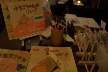 Книжка с картинками на японском и корейском, а рядом записная книжка, где посетители могут обменяться мнениями о кафе и арт-работах. 