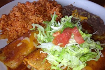 <p>The enchilada plate is a bit spicy and comes with three enchiladas topped with lettuce, refried beans, and Mexican rice</p>