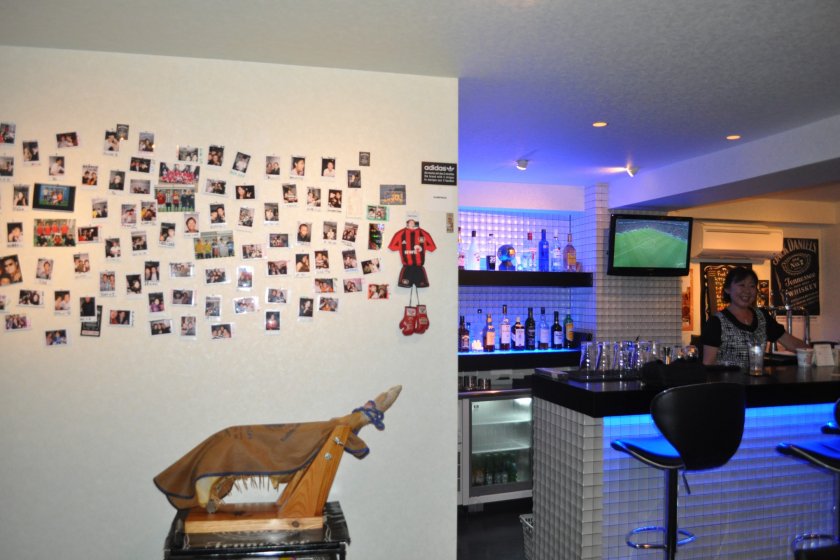 A jamón ibérico leg next to a wall filled with guest\'s pictures