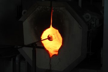 Heating the molten glass in the burner to make it malleable