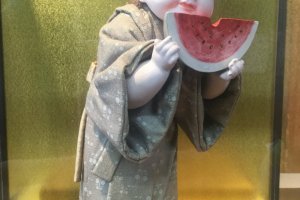 Delightful doll of a child eating a watermelon.