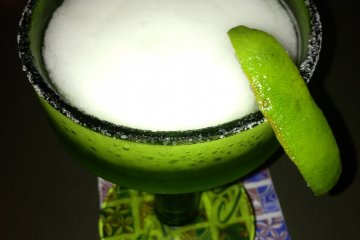 <p>Margaritas are served very cold in a salt-rimmed frosted glass with a slice of lime</p>