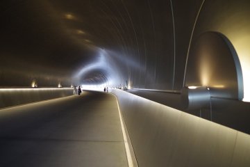 Metallic interior of the tunnel built of sound proof technique that is unusually quiet. You enter a state of calmness and prepare for the surprising scenery ahead.