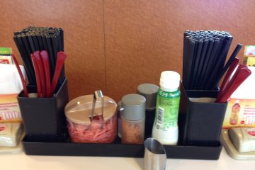 <p>Chopsticks and spoons are readily available at the tables and counters in Sukiya, as are condiments, the ticket holder, and the ordering bell</p>
