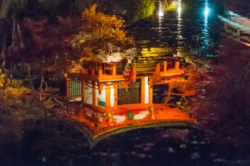 Храм в ярких красных цветах четко отражается на поверхности воды