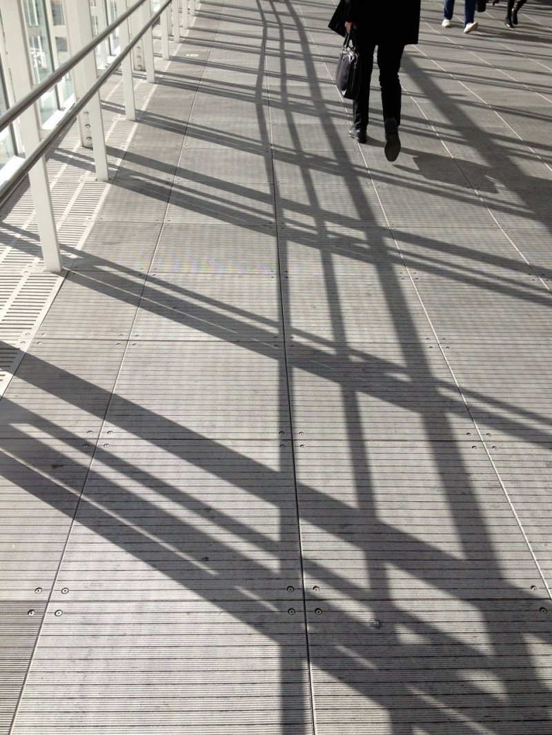 Overhead walkway Shibuya station: Footsteps crossing diagonal shadows