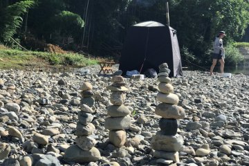 Creative people build stone art at the river's shore