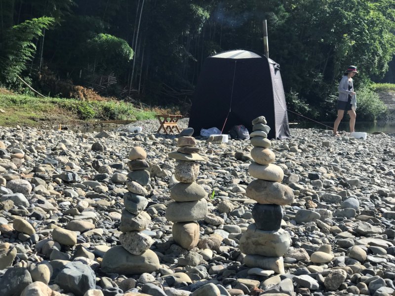 Creative people build stone art at the river's shore
