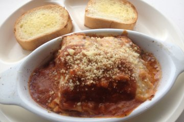 <p>The lasagna and garlic bread set sprinkled liberally with parmesan cheese</p>