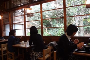 There are a few tables with chairs near the window.