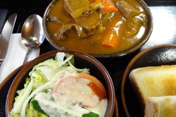 A lunch set includes a bowl of beef stew, rice or a slice of bread, a small salad, and coffee or tea for 2625 yen.