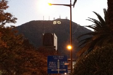 走出八幡站后远望到的皿仓山，为了纪念北九州市制50周年，皿仓山山体上点缀着巨大的“50”字样