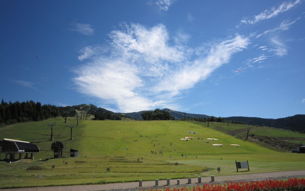 Turfy ski slope. Paragliders can be seen in the autumn, mackerel sky