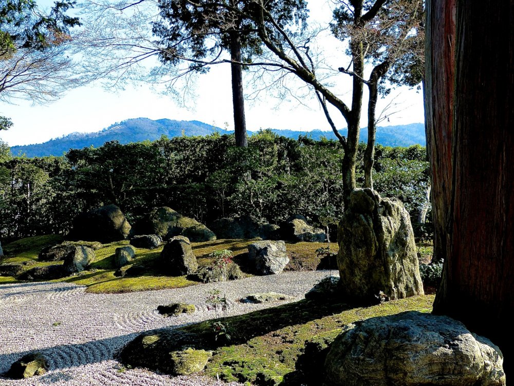The garden provides a distant view (mountains), closer view (hedge), and immediate view (rock, moss and sand)