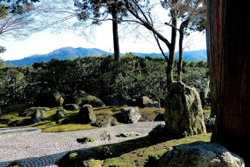 The garden provides a distant view (mountains), closer view (hedge), and immediate view (rock, moss and sand)