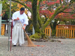 A monk tidying the grounds before the morning visitors arrive