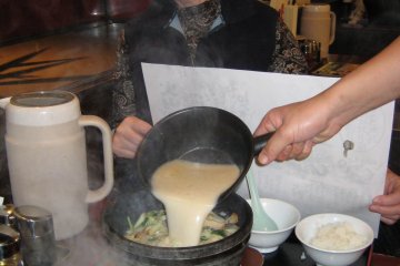 <p>Steam, noise and bubbling result as the ramen is poured into the heated stone bowl by the server</p>