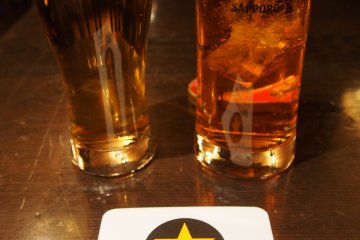<p>ส่วนของจุดบริการเครื่องดื่ม แก้วด้านขวาคือเบียร์ซัปโปโร Black Label ที่ขึ้นชื่อของยี่ห้อนี้ ส่วนแก้วด้านขวาคือน้ำผลไม้สำหรับผู้ที่ไม่ดื่มเบียร์</p>